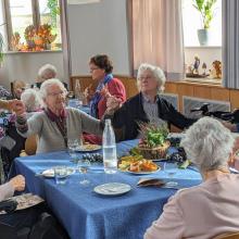 Seniorinnen tanzen mit Mitarbeiterinnen unseres Altenpflegeheims am Tisch.
